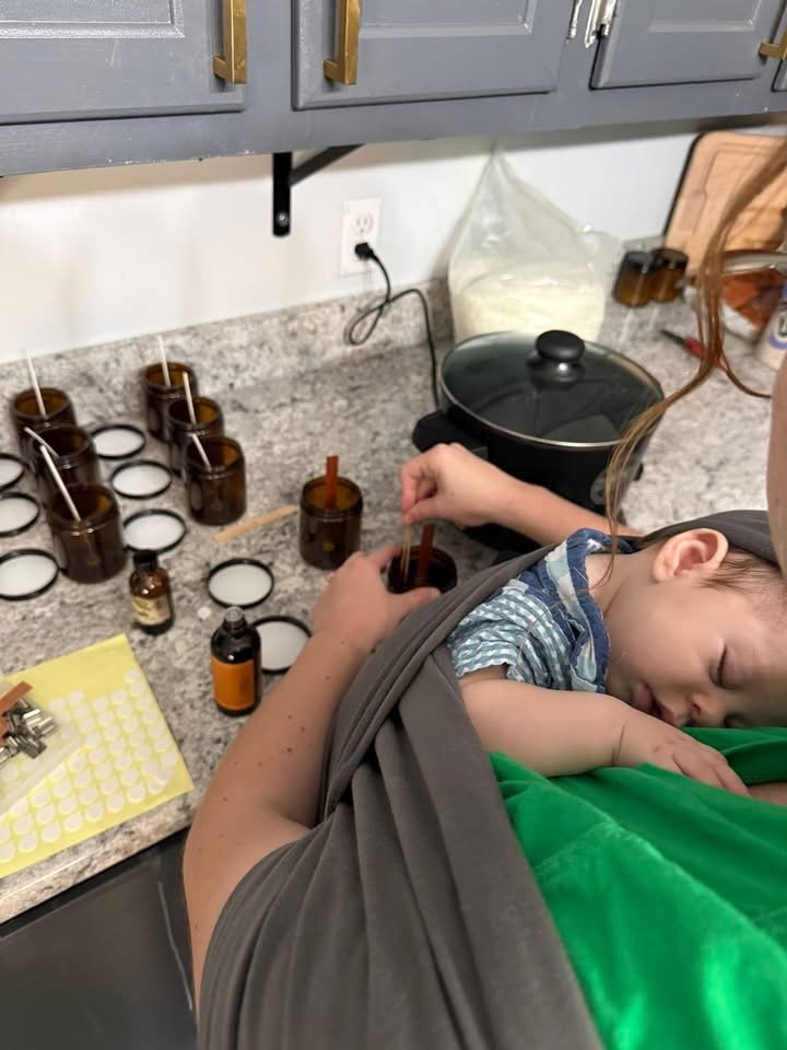 woman holding baby while making candles
